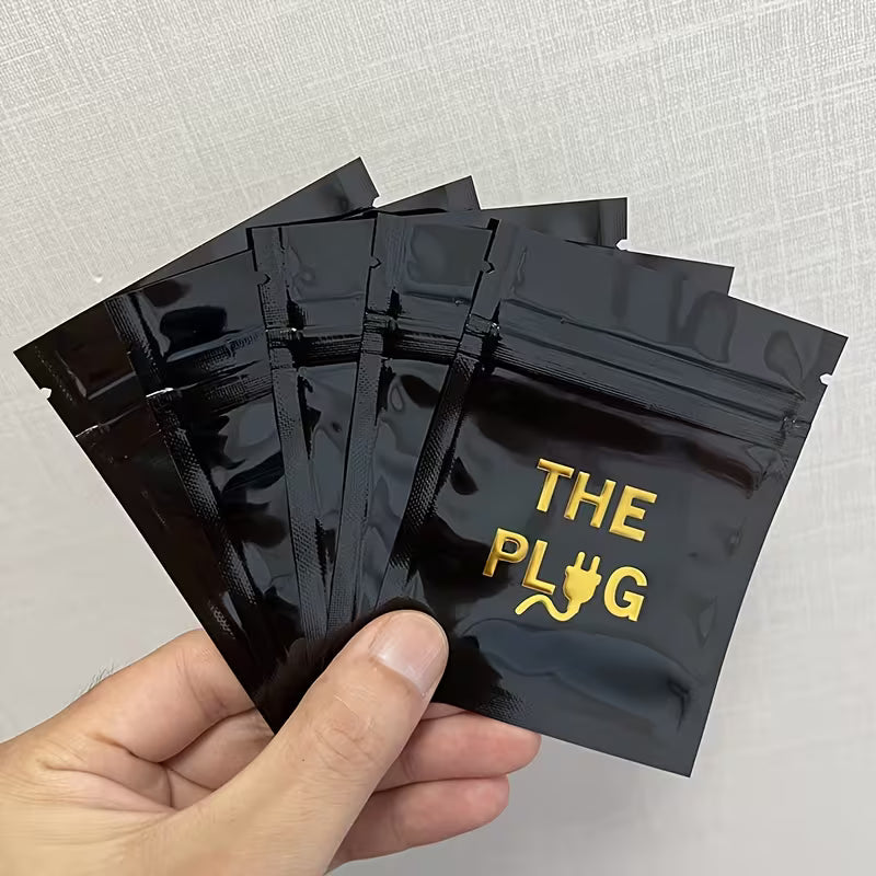 Black packaging with 'THE PLUG' branding held by a hand against a light gray background